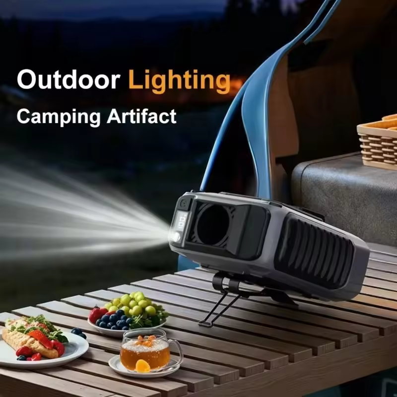 Ventilador encendido con luz LED frontal sobre una mesa de madera de campamento.