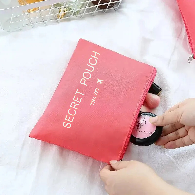 Manos guardando artículos de maquillaje dentro de una bolsa plana rosada con cierre.